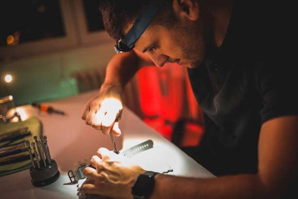 Man repairs watch using a headlamp with focused beam.