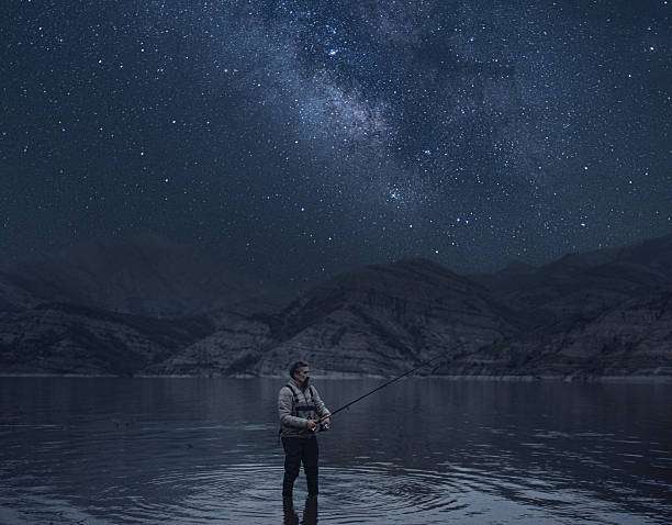 Fisherman under starry sky with headlamp on