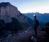 Woman with headlamp on mountain trail at dusk.