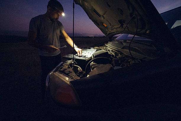 Man with a headlamp fixing his car engine at night.