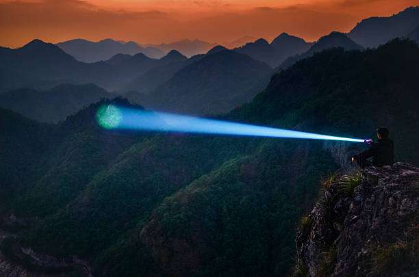Man with a powerful headlamp beam on a mountain peak