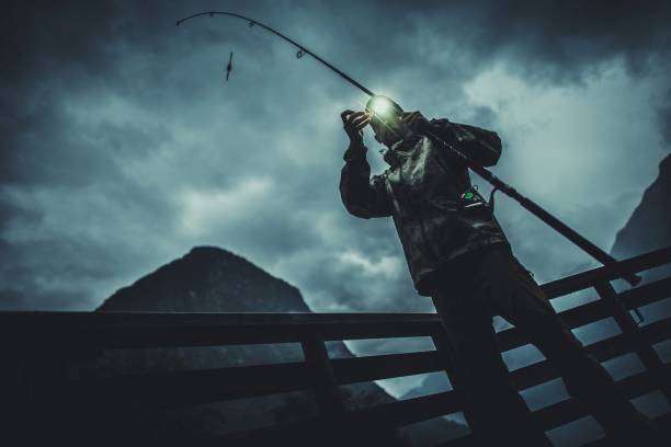 Angler fishing at night with bright headlamp illumination