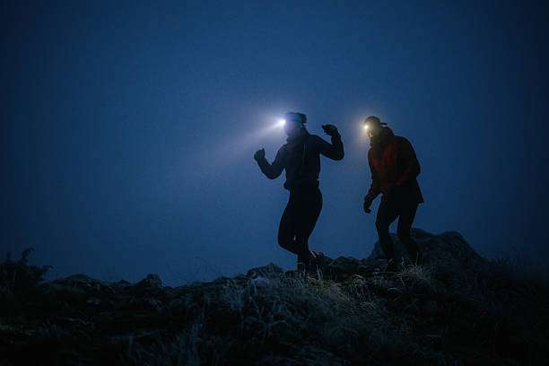 Two runners with headlamp beams in dark.