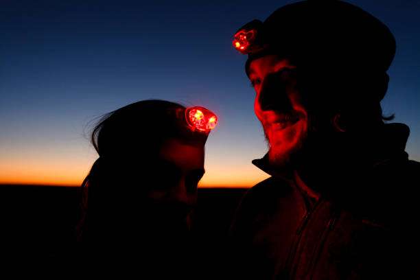 Couple smiling with red headlamp lights at dusk