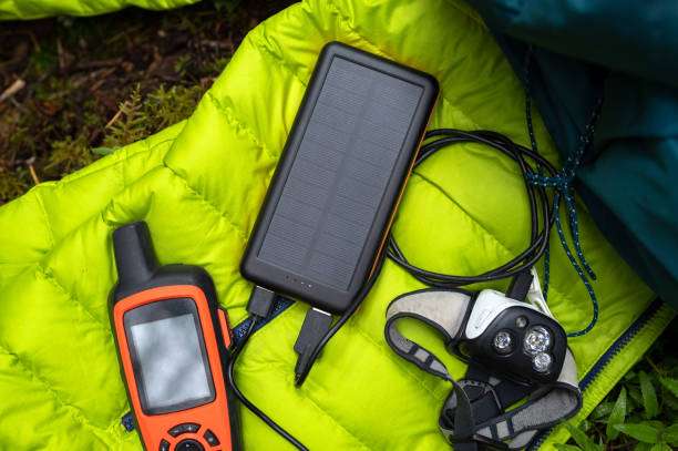 Camping gear: GPS, solar power bank, and a black headlamp on a yellow jacket.