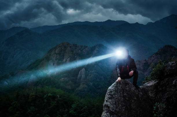 Hiker with bright headlamp on mountain at night
