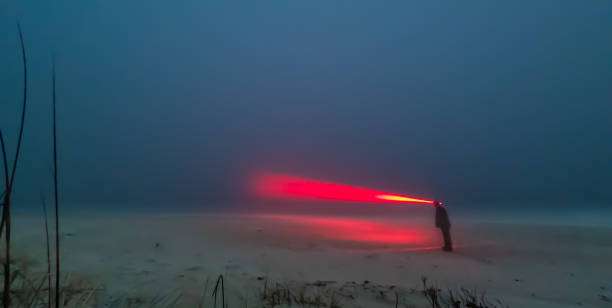 Person standing in fog with a red headlamp beam.