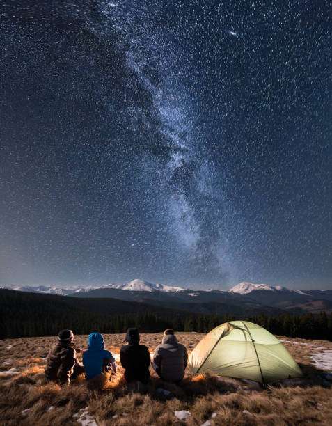 Friends camping under the Milky Way, no headlamp visible.